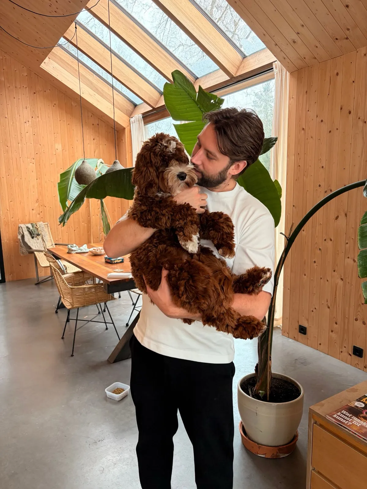 Stijn Rolink thuis, met labradoodle Caes in zijn armen